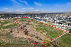 West facing aerial perspective of suburban area with property parcel outlined and a mountainous background