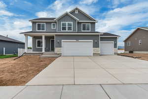 Craftsman-style home featuring stone siding, a porch, board and batten siding, concrete driveway, and a garage