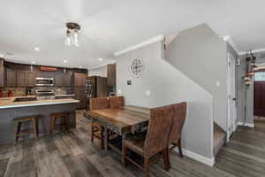 Dining space with crown molding, dark wood-style flooring, stairs, and recessed lighting