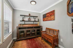 Sitting room featuring ornamental molding and dark wood-style flooring