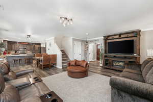 Living room featuring stairway, crown molding, wood finished floors, and recessed lighting