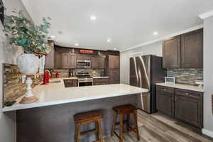 Kitchen featuring crown molding, appliances with stainless steel finishes, decorative backsplash, light countertops, and light wood-style flooring