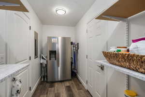 Kitchen featuring stainless steel fridge, wood finished floors, and light stone counters