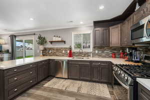 Kitchen featuring appliances with stainless steel finishes, light countertops, plenty of natural light, light wood-style floors, and crown molding