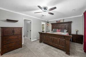Bedroom with light carpet, crown molding, a ceiling fan, and ensuite bathroom