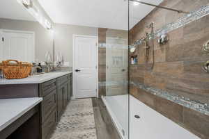 Full bathroom featuring a tile shower, vanity, and wood finished floors