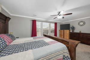 Carpeted bedroom featuring crown molding and a ceiling fan