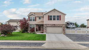 Traditional-style home with driveway, an attached garage, brick siding, and a gate
