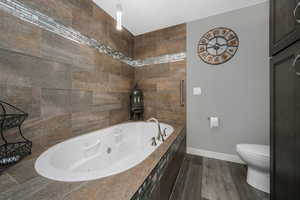 Full bath with a whirlpool tub and wood finished floors