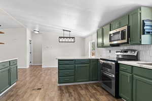Kitchen featuring green cabinets, appliances with stainless steel finishes, a peninsula, and light countertops