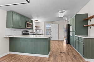 Kitchen featuring green cabinets, open shelves, a peninsula, and light countertops