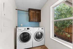 Washroom featuring cabinet space, washing machine and clothes dryer, and wood finished floors
