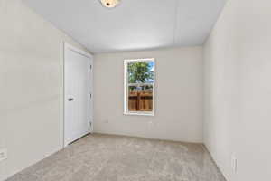 Carpeted spare room featuring vaulted ceiling