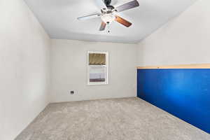 Carpeted spare room featuring a ceiling fan