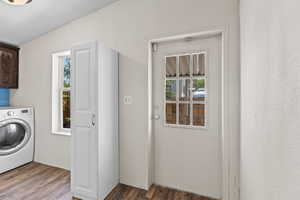 Laundry room with cabinet space, washer / dryer, and wood finished floors