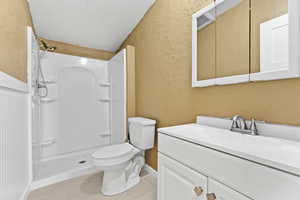Bathroom featuring a textured wall, vanity, a shower, and tile patterned floors
