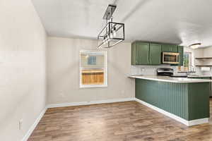 Kitchen with green cabinetry, light countertops, and light wood-style floors