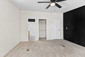 Unfurnished bedroom with carpet floors, ensuite bath, and ceiling fan
