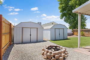 View of shed featuring an outdoor fire pit and a fenced backyard