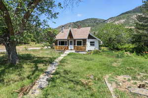 View of front of property featuring a mountain view, roof with shingles, and a chimney
