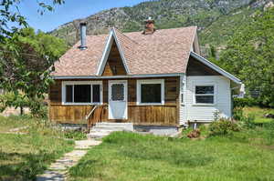 View of front of home featuring entry steps, roof with shingles, a chimney, and a mountain view