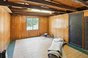Interior space with hardwood / wood-style flooring, wooden walls, and beamed ceiling