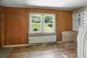 Spare room featuring radiator, washer / clothes dryer, hardwood / wood-style flooring, and ornamental molding