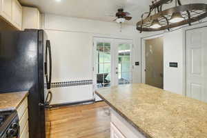 Kitchen featuring radiator, black appliances, french doors, light wood-type flooring, and ceiling fan