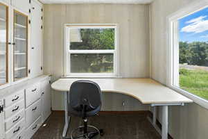 Home office with built in study area and dark carpet