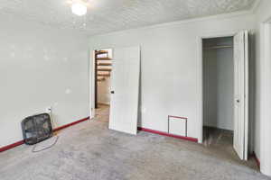 Unfurnished bedroom featuring a spacious closet, carpet flooring, and a textured ceiling