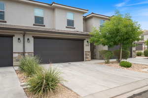 Traditional home with stone siding, concrete driveway, stucco siding, and an attached garage