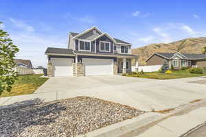 Craftsman inspired home with concrete driveway, stone siding, a garage, and a mountain view