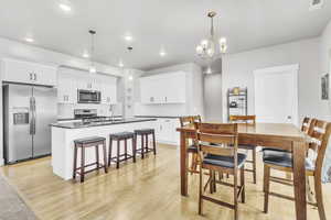 Dining space with recessed lighting, light wood-style flooring, and a chandelier