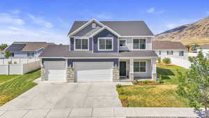 Craftsman-style home with stone siding, concrete driveway, roof with shingles, and a mountain view