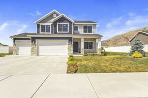 Craftsman house with stone siding, driveway, a porch, a mountain view, and a garage