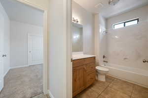 Bathroom with washtub / shower combination, vanity, and tile patterned flooring