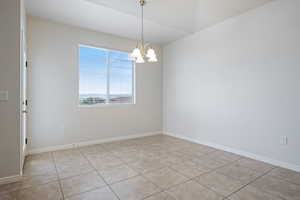 Unfurnished room with a chandelier and light tile patterned flooring