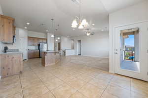 Kitchen with a chandelier, recessed lighting, freestanding refrigerator, open floor plan, and light tile patterned flooring
