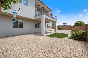 Rear view of house with a balcony, a fenced backyard, stucco siding, and a patio