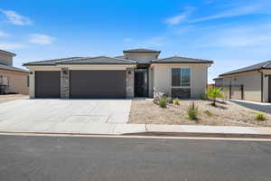 Prairie-style house with an attached garage, a tile roof, concrete driveway, stone siding, and stucco siding