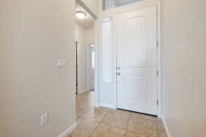 Foyer with light tile patterned floors and baseboards