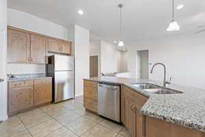 Kitchen featuring appliances with stainless steel finishes, light tile patterned flooring, decorative light fixtures, light stone countertops, and recessed lighting