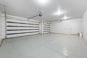 Garage featuring baseboards and a garage door opener