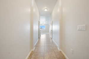 Hall with light tile patterned flooring and baseboards