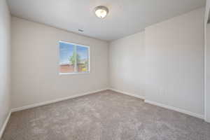 Carpeted spare room featuring baseboards