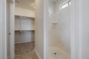 Full bathroom featuring a shower stall, tile patterned floors, and a walk in closet