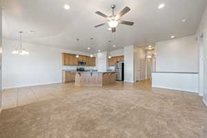 Unfurnished living room with light tile patterned flooring, a ceiling fan, recessed lighting, light carpet, and a chandelier