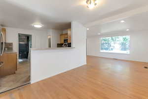 Kitchen featuring light wood-type flooring, recessed lighting, light countertops, a peninsula, and fridge