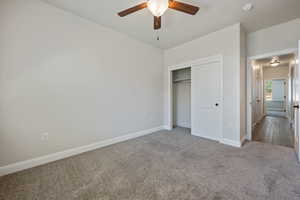 Unfurnished bedroom featuring carpet floors, a closet, and ceiling fan