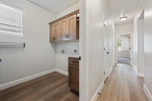 Laundry area with electric dryer hookup, cabinet space, washer hookup, and wood finished floors